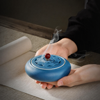 Blue ceramic lotus incense burner held in two hands